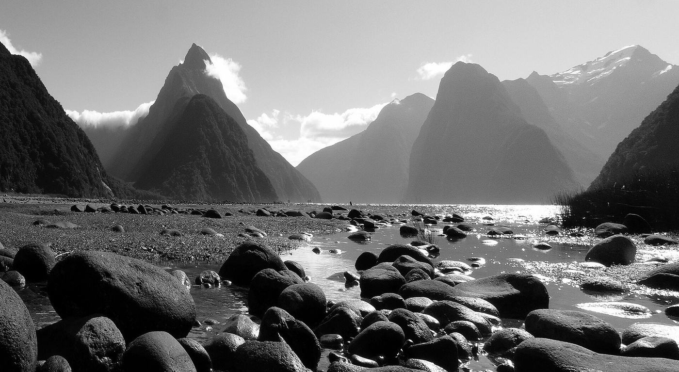 Piopiotahi / Milford Sound, peaks rising from the water over a stony shore